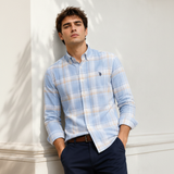 Man wearing sky blue plaid shirt against white architectural wall