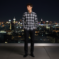 Man wearing black white plaid shirt on urban rooftop at night