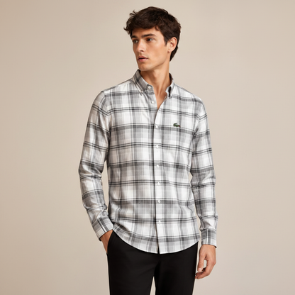 Man wearing light grey plaid shirt against warm beige studio background