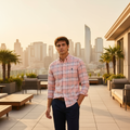 Man wearing pink plaid shirt on rooftop at golden hour