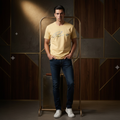 Man wearing butter yellow Rare Rabbit script tee against moody dark background with spotlight