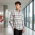 Man wearing light grey plaid shirt in modern office lobby