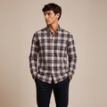 Man wearing grey burgundy plaid shirt against warm beige studio background